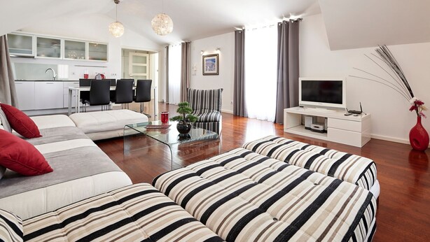 Ein modernes Wohnzimmer mit einer Couch, einem Glastisch und einer TV-Konsole.