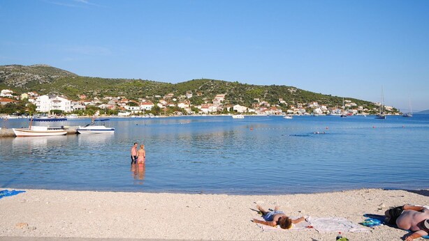 Une plage avec des bateaux, un ciel dégagé et des maisons en arrière-plan.