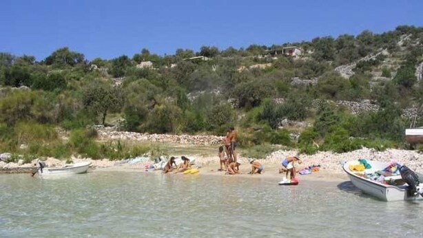 Ein Strand mit klarem Wasser, Booten und Menschen.