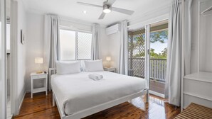 A bedroom with a bed, a ceiling fan, a window, a nightstand, and a view of the outdoors. - Bright 3-Bed Home in Leafy Annerley (Annerley)
