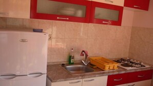 A kitchen with a white refrigerator, a sink, a gas stove, and red cabinets.