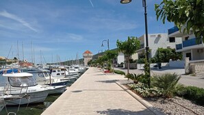 Ein Yachthafen mit vertäuten Booten, einem gepflasterten Weg und Gebäuden mit Balkonen.