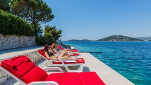 A poolside area with lounge chairs and a stone wall. - Strandnahes Ferienhaus mit Garten in Ražanj by Interhome (Rogoznica/Ražanj)