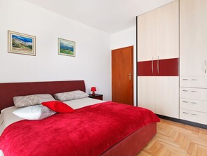 A bedroom with a bed, a nightstand, a wardrobe, and two framed pictures on the wall.