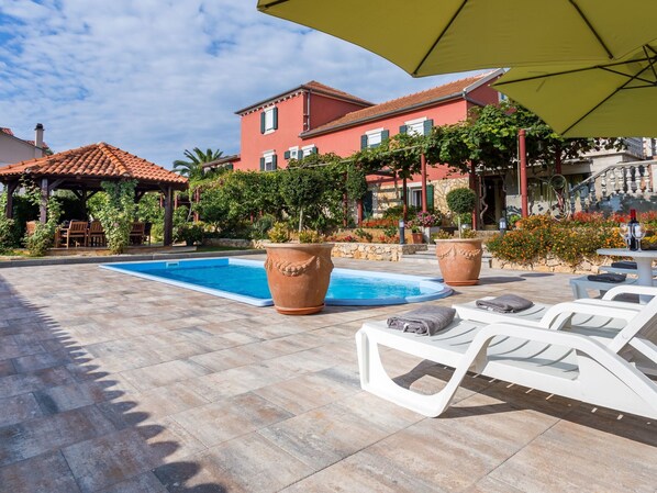 Un espace piscine avec des chaises longues et une pergola.