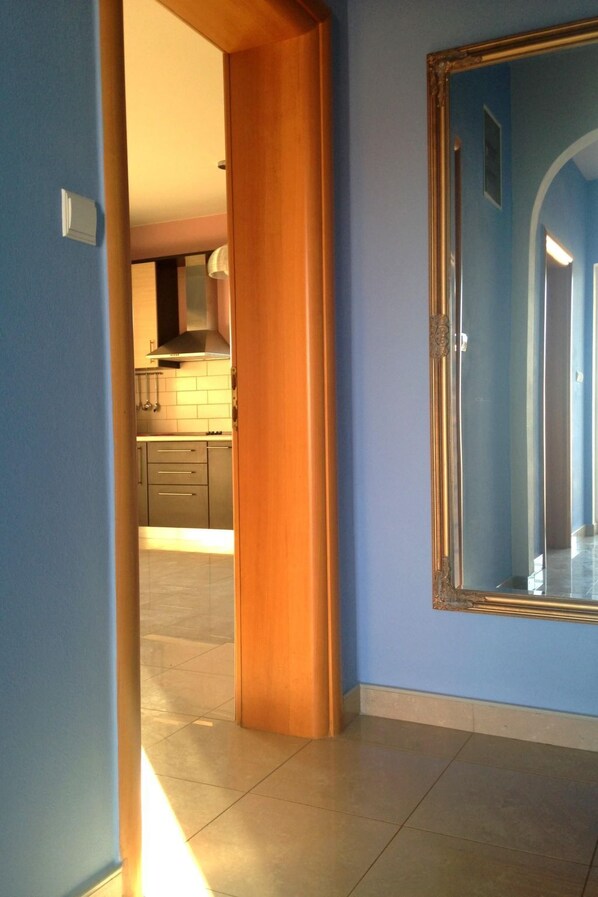 A hallway with a wooden door frame and a large mirror on the wall.