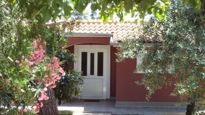 A red building with a white door, surrounded by greenery and a stone pathway. - Strandnahes Haus Lolinka mit schattiger Terrasse by Interhome (Zadar/Bibinje)