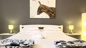 A neatly made bed with white linens and two folded blankets, two bedside lamps, and a wall-mounted artwork of a horse's head. - Strandnahes Haus Lolinka mit schattiger Terrasse by Interhome (Zadar/Bibinje)