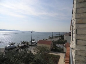 Une vue sur la côte, avec un fourgon blanc garé près d’un bâtiment dont le toit est recouvert de tuiles rouges.