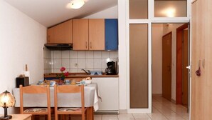 Ett kompakt kök med träskåp, ett matbord med stolar, en kaffebryggare och en liten bordslampa.