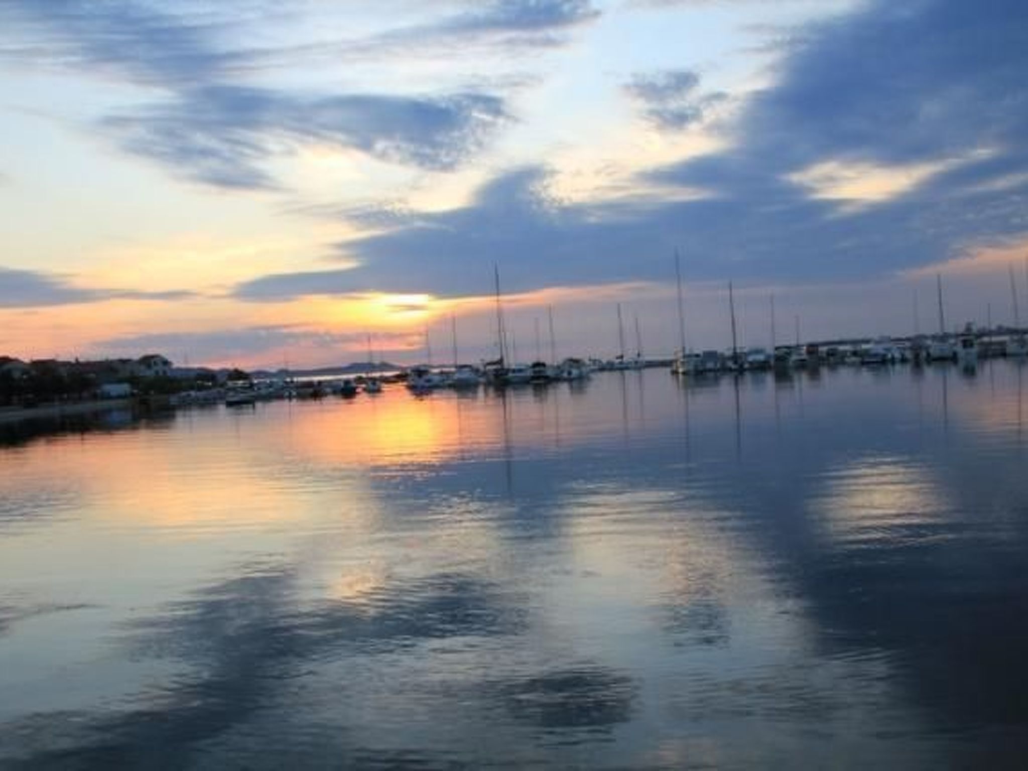 A marina with boats docked at calm water during sunset.