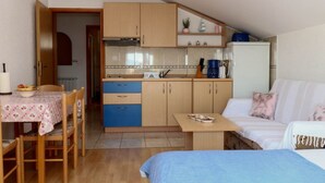 Eine kompakte Küche mit Holzausstattung, einem Esstisch mit Stühlen und einer Küchenzeile.