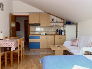 A compact kitchen with wooden cabinets, a dining table with chairs, and a kitchenette area. - Apartment im zweiten Stock mit Blick aufs Meer by Interhome (Zadar/Bibinje)
