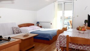 Ein gemütliches Zimmer mit einem Bett, einem kleinen Schreibtisch, einem Stuhl und einem Esstisch.
