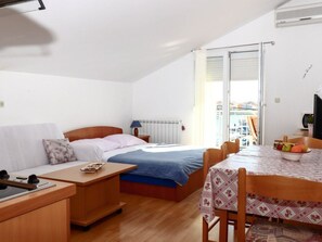 A compact room with a bed, a small desk, a chair, and a dining table. - Apartment im zweiten Stock mit Blick aufs Meer by Interhome (Zadar/Bibinje)