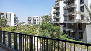 Un moderno edificio de apartamentos con varios balcones, rodeado de vegetación y palmeras.