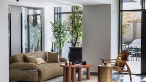 Una sala de estar moderna con un sofá, una mesa de centro, una silla y una planta grande en maceta.