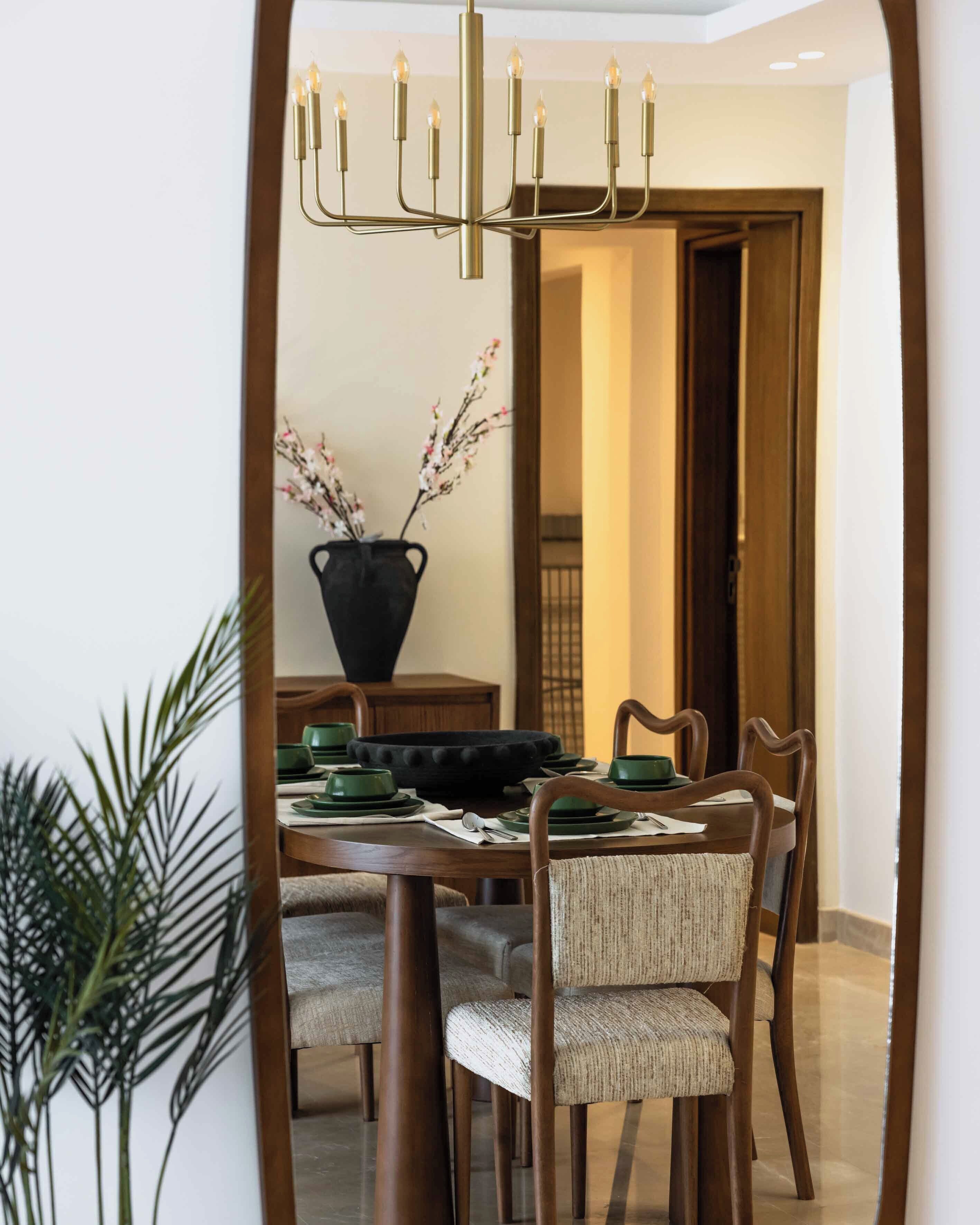 A dining area with a chandelier, a vase with branches, and a table set for four.