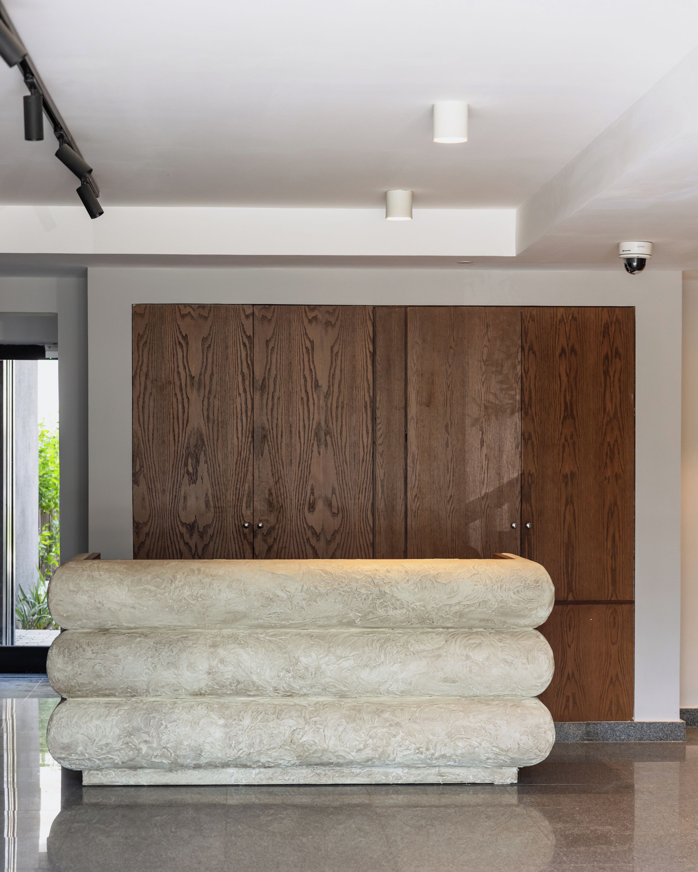 Un intérieur moderne avec une grande armoire en bois, un canapé blanc à la texture intéressante et un design de plafond élégant.