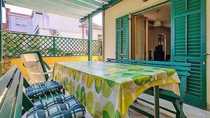 An outdoor patio with a table and benches, a covered seating area, and a building entrance with green shutters. - mit Terrasse by Interhome (Zadar)