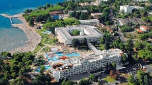Ein Luftbild eines Hotels mit einem großen Gebäude, einem Schwimmbad und einer Strandanlage.