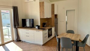 A compact kitchen with a TV, a coffee maker, and a refrigerator. - mit Blick auf das Wasser by Interhome (Vir)