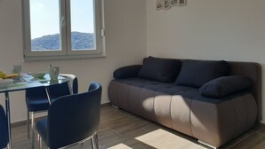 Un salon avec un canapé, une table à manger et des chaises, ainsi qu’une fenêtre donnant sur un paysage montagneux.