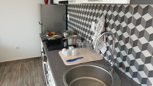 Une cuisine moderne avec un dosseret à motifs noir et blanc, des appareils en acier inoxydable et un évier avec un robinet.
