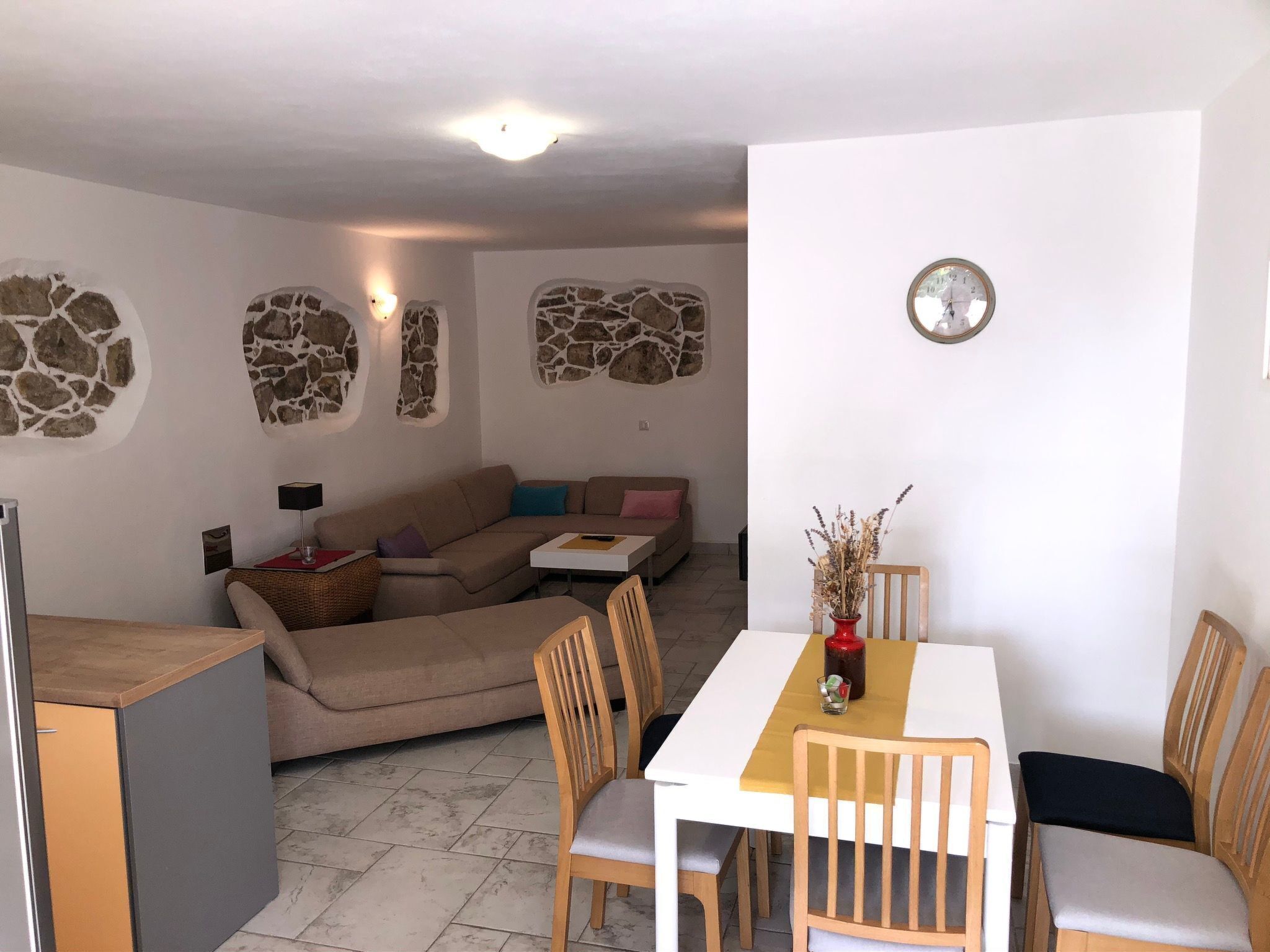 A cozy living area with a sofa, a dining table with chairs, and a kitchen area.