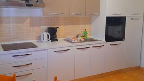 A compact kitchen with white cabinets, a microwave, a kettle, and a sink. - Fantastisches Haus nur 700m vom Strand entfernt by Interhome (Rab/Kampor)