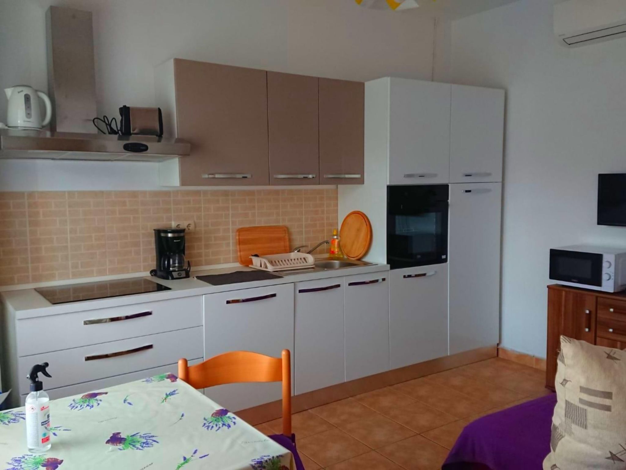 A compact kitchen with white cabinets, a microwave, and a coffee maker.