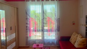 Ein Zimmer mit einem roten Sofa, einem kleinen Tisch und einem Schrank.