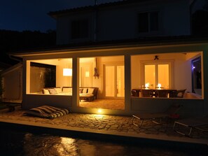 A house with an open patio area featuring a pool, a dining area with a table and chairs, and a seating area with a sofa and cushions. - Villa Prislin by Interhome (Rab/Kampor)