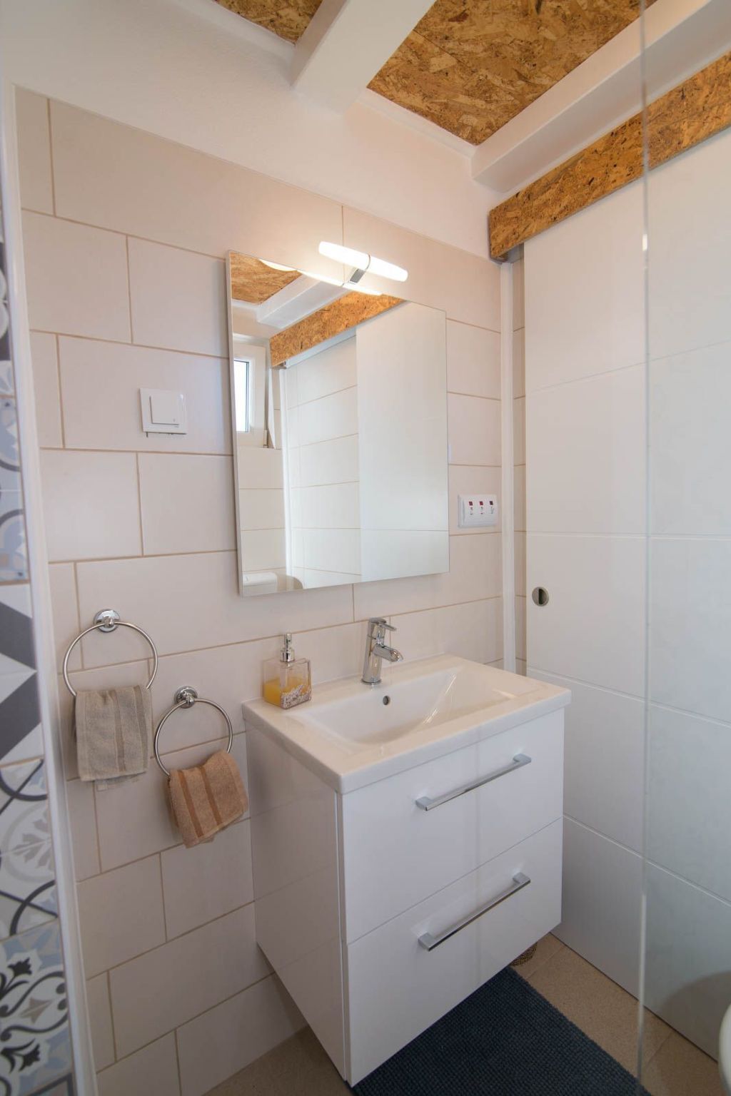 Une salle de bain avec un meuble-lavabo blanc, un miroir et un porte-serviettes.
