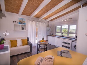 A modern room with a wooden ceiling, a sofa with cushions, a dining table with fruit, a kitchen with a window, and a washing machine. - Andrej in Veli Losinj by Interhome (Lošinj / Veli Lošinj)