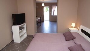Ein Schlafzimmer mit einem Bett, einem Fernseher, einem Nachttisch und einem Schreibtisch.
