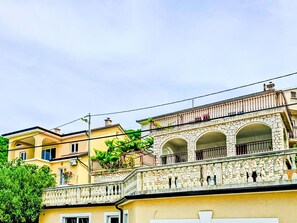 Ein mehrstöckiges Gebäude mit einer Stein-Fassade, Balkonen und blauem Himmel.