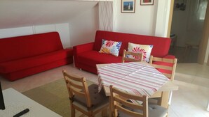 Ein Wohnzimmer mit einem roten Sofa, einem Holzespeisetisch mit Stühlen und einer Tischdecke mit Muster.