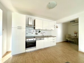 Een koelkast, een microgolfoven, een oven, kookgerei, borden en bestek