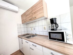 A compact kitchen with a microwave, coffee maker, and a sink. - Wohnung in Dramalj mit Möbliertem Balkon by Interhome (Crikvenica/Dramalj)