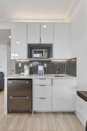 A modern kitchen with white cabinetry, a microwave, a coffee maker, and a sink. - Special/Pool/StepsToBeach/Terrace Studio (Palm Beach)