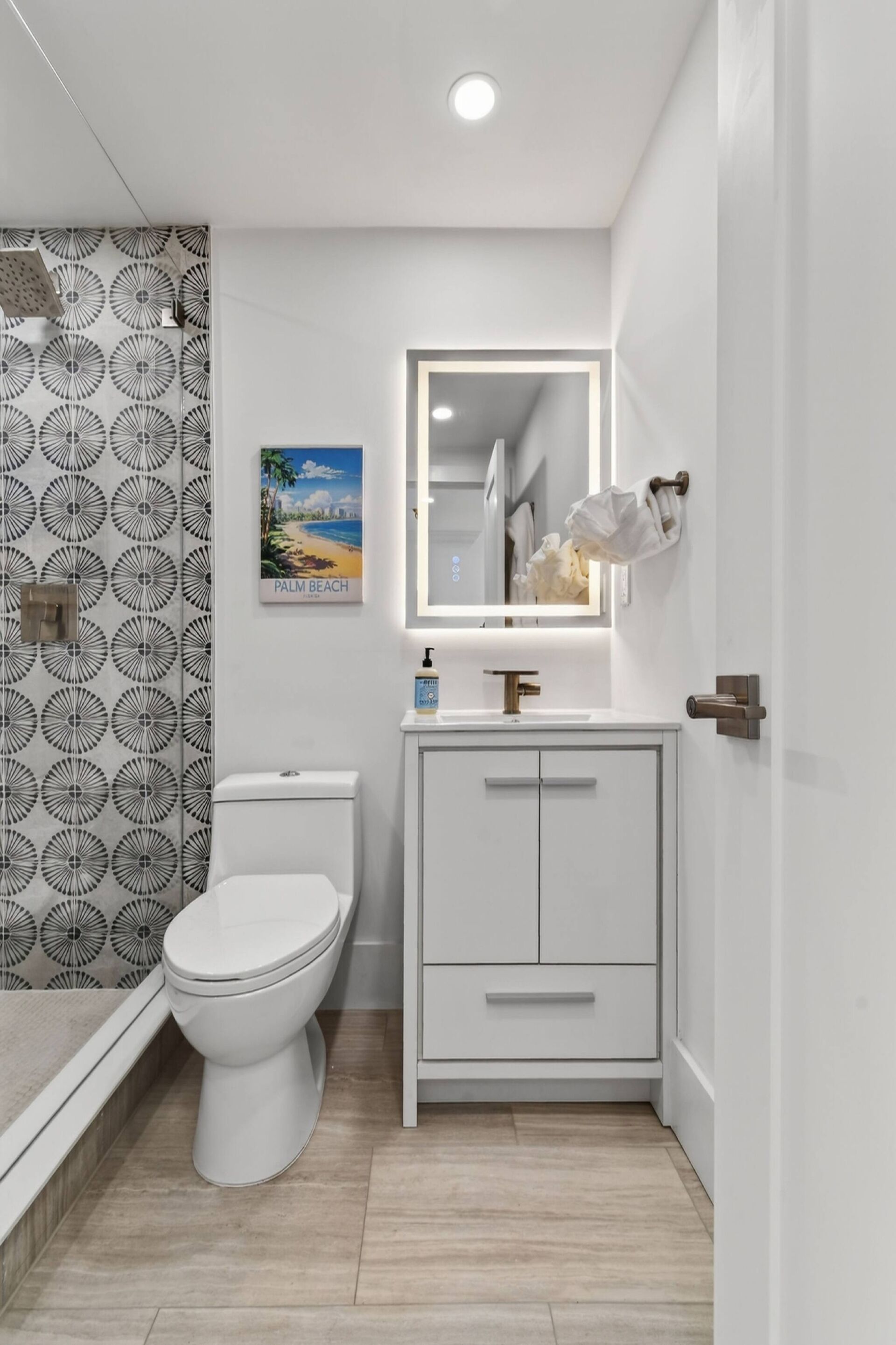 Un baño con inodoro, lavamanos con espejo y zona de ducha.