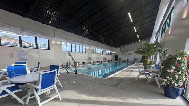 An indoor swimming pool with blue chairs and potted plants. -  Spacious 3-bed, 2-bath condo with large all-season patio & optional Boat Slip. (Lake Ozark)