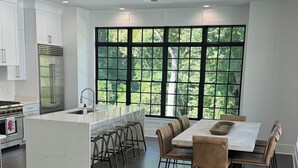 Una cucina moderna con isola centrale, elettrodomestici in acciaio inossidabile e ampie finestre con vista sul verde.