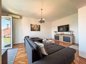 A modern living room with a sofa, a small round table, a TV, and a chandelier. - Schöne Wohnung in Dramalj by Interhome (Crikvenica/Dramalj)