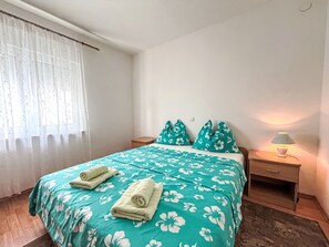 A bedroom with a bed, two nightstands, a lamp, and a window with curtains. - Appartement in Dramalj mit Möbliertem Balkon by Interhome (Crikvenica/Dramalj)