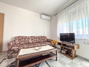A living room with a sofa, a coffee table, a television, and a radio. - Appartement in Dramalj mit Möbliertem Balkon by Interhome (Crikvenica/Dramalj)