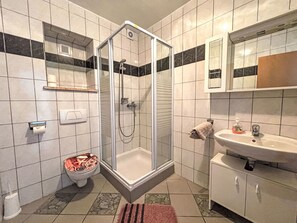 A bathroom with a glass-enclosed shower, a toilet with a marble seat, a sink with a mirror, and a towel rack. - Appartement in Dramalj mit Möbliertem Balkon by Interhome (Crikvenica/Dramalj)