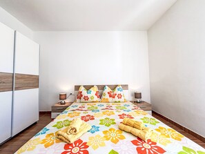 A bedroom with a bed, two bedside tables, a nightstand, a wooden headboard, and a wall-mounted wardrobe. - Wohnung in Dramalj mit Möbliertem Balkon by Interhome (Crikvenica/Dramalj)