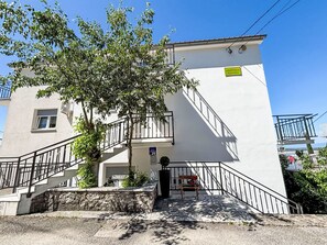 A building with a staircase, a sign reading 'APARTMANI SLAVICA,' and a bench with flowers. - Wohnung in Dramalj mit Möbliertem Balkon by Interhome (Crikvenica/Dramalj)